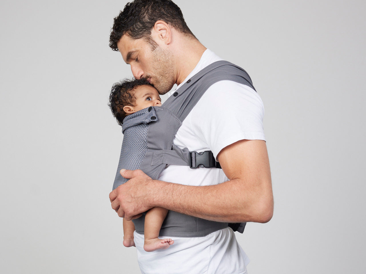 Man kisses the head of baby he is carrying in the Izmi Breeze Baby Carrier