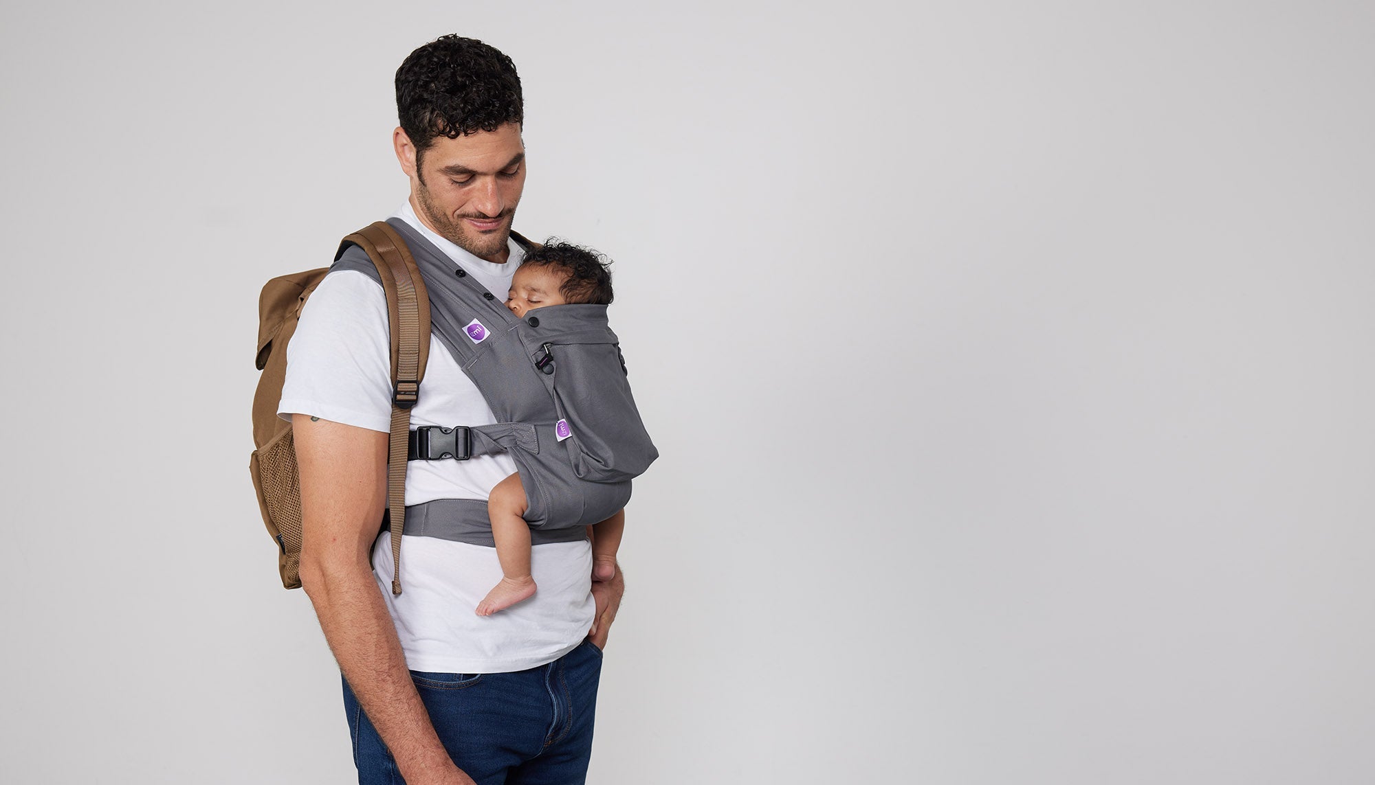 Man carries baby on his front in Izmi Baby Carrier with Zip Pocket