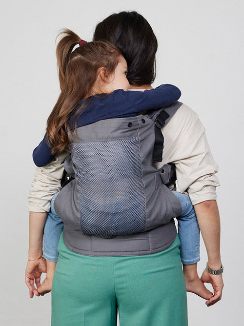 Woman carries toddler on her back in Izmi Breeze Baby Carrier, back view
