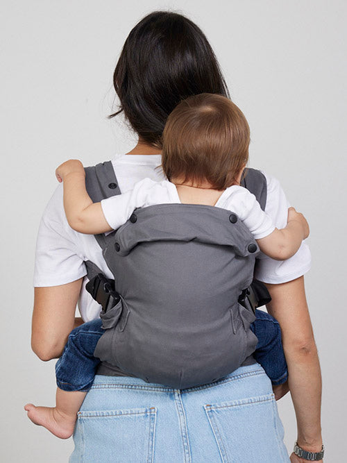Woman carries baby on her back in Izmi Baby Carrier, back view