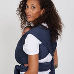 Woman carries baby facing towards her in Izmi Baby Wrap in Slate colour, back view