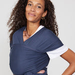 Woman carries baby facing towards her in Izmi Baby Wrap in Slate colour