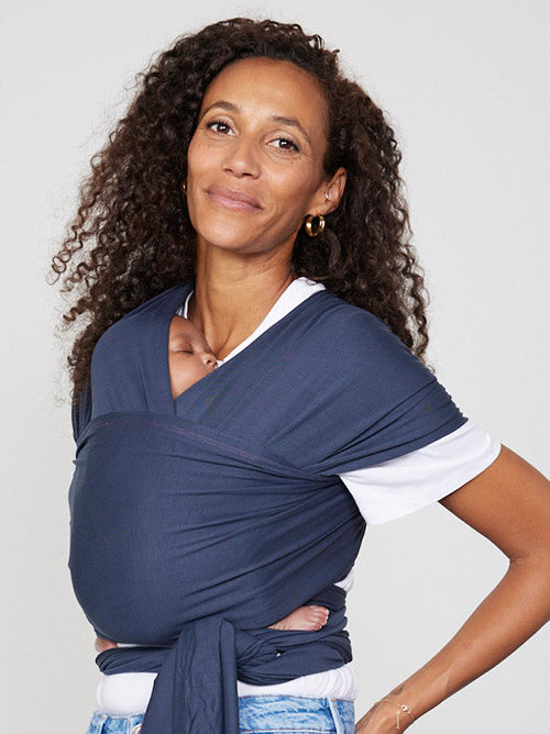 Woman carries baby facing towards her in Izmi Baby Wrap in Slate colour