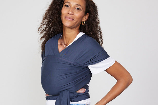 Woman carries baby on her front in Izmi Baby Wrap in Slate