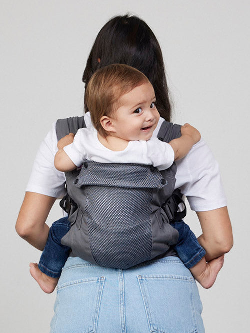 Woman carries baby on her back in Izmi Breeze Baby Carrier, back view