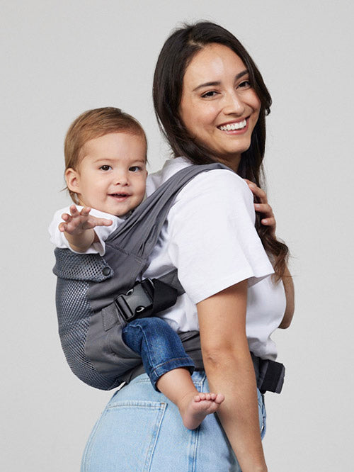 Woman carries baby on her back in Izmi Breeze Baby Carrier, side view