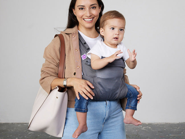 Woman carries baby facing forwards in Izmi Breeze Baby Carrier