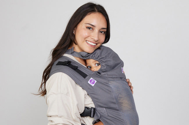Woman carries toddler on her front in Izmi Breeze Toddler Carrier with attached Sleep Hood