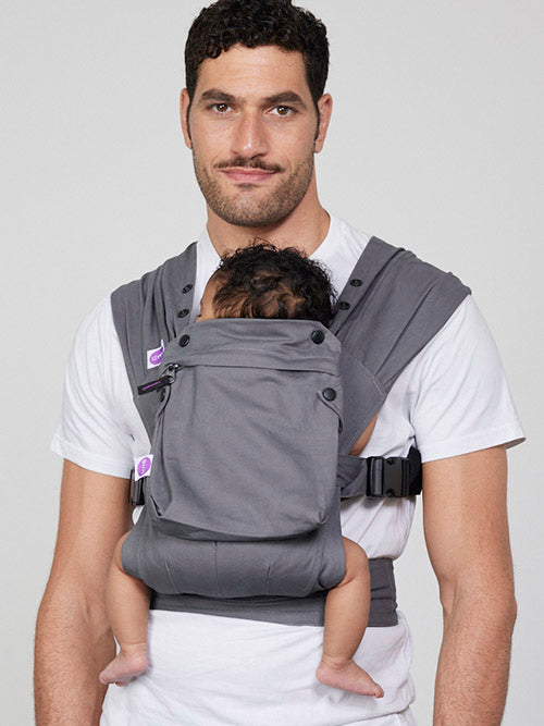 Man carries baby on his chest in Izmi Baby Carrier with Zip Pocket attached