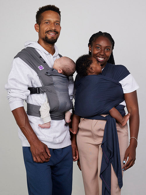 Man carries baby on his front in Izmi Breeze Baby Carrier, woman carries baby in Izmi Baby Wrap