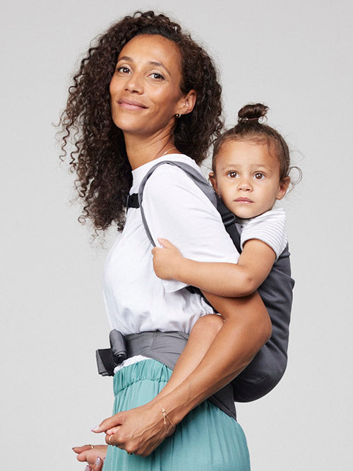 Woman carries toddler on her back in Izmi Toddler Carrier