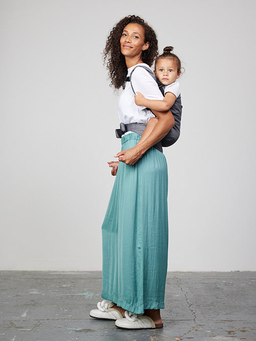 Woman carries toddler on her back in Izmi Toddler Carrier