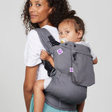 Woman carries toddler on her back in Izmi Toddler Carrier with Zip Pocket attached