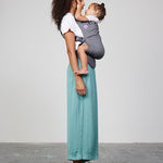 Woman carries toddler on her front in Izmi Toddler Carrier, side view