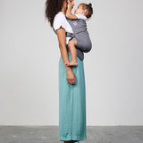 Woman carries toddler on her front in Izmi Toddler Carrier, side view