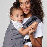 Woman carries toddler on her front in Izmi Toddler Carrier